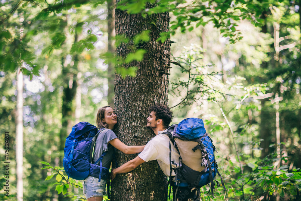 Wall mural hiking couple. young couple with backpacks hugging tree and having fun