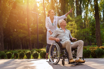 Doctor show something interest to old man in wheelchair