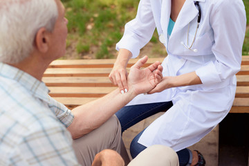 Obraz premium Doctor measures the patient's pulse while sitting in the park