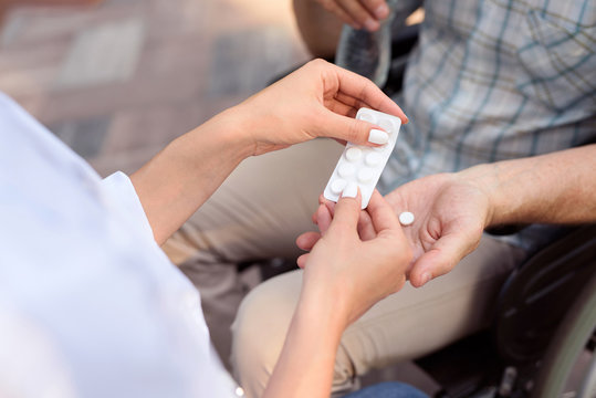 Doctor gives pills to a patient sitting on the street