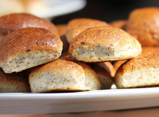 Freshly baked wheat buns with poppy seeds on a white plate
