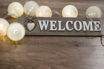 Handmade text welcome with multicolor decorative lights on the wooden table