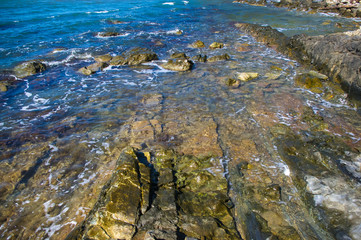 rocky sea shore with pebble beach, waves with foam