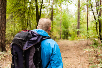 Hiker with backpack is walking in the autumn forest.