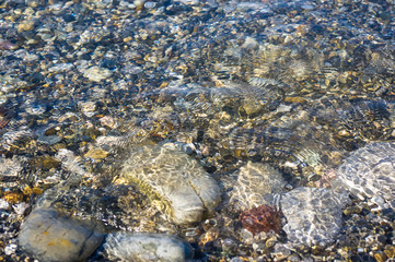 sea pebble beach with multicoloured stones, waves with foam