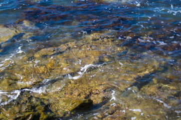 rocky sea shore with pebble beach, waves with foam
