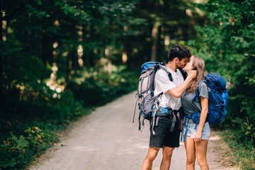 Fototapeta na wymiar Hiking couple. Young couple with backpacks kissing