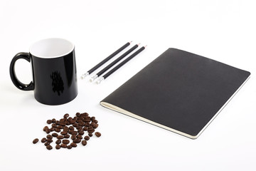 Mock up with black mug, raw coffee beans, black pens and black notebook with white background