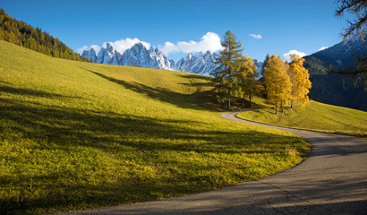 Magical charming beautiful autumn landscape with a winding road and yellow larch on a background of mountains in the Dolomites. The Italian Alps. (Meditation, anti-stress, relaxation - concept)