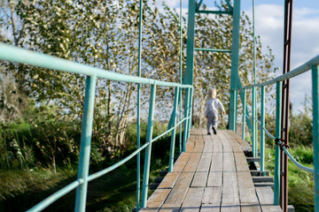 Old wooden pendant bridge with a child, The Urals village, Russia