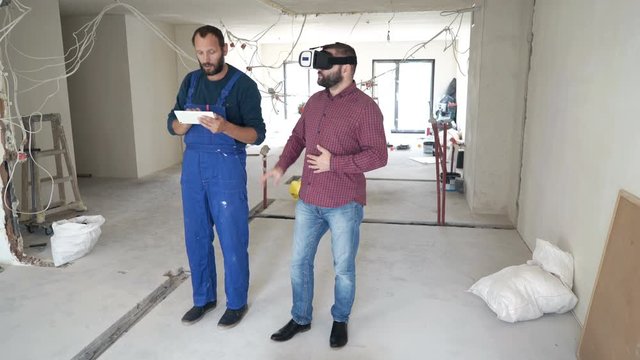 Male architect and worker with vr goggle and tablet setting up project at new home
