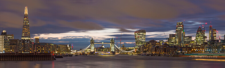 London - The panorama of the Tower bridge, riverside and skyscrapers at dusk with the dramatic clouds.