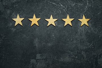 Five stars in a row on a black rustic cement boards. Conceptual of service rating and quality of trade. Top view, copy space for your text. - 175235880