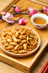 Spicy peanuts in wooden plate on bamboo plate