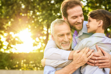 Obraz premium Family meeting. A man and a boy came to see their grandfather who sits in a park on a wheelchair