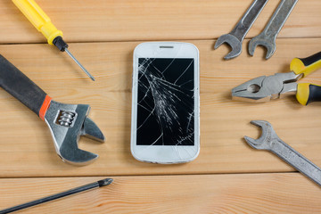 Mobile phone next to tools on wooden background. service, repair concept