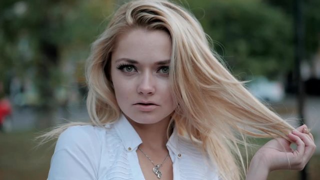Portrait of young happy blonde business woman in the city. Slow motion. Beautiful girl in white sexy blouse in the street.