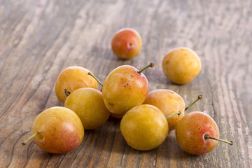 Ripe yellow plums on old wooden table. Top view.