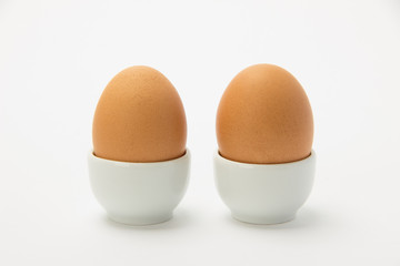 Two beautiful brown eggs on a stand on a white background