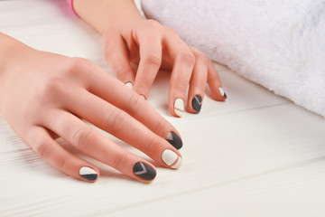 Obraz na płótnie Canvas Girl hands with beautiful manicure. Female hands with fashion design nails in beauty salon. Black and white manicure art design.