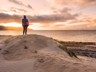 A woman watching sunset over the Atlantic ocean, West coast of Ireland., The Burren region.