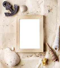 vintage wooden photo frame on craft paper with sand and sea shells mock up. Travel, summer concept. Text space
