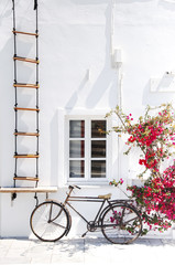 Fototapeta na wymiar Santorini Island, Oia, Greece. Traditional white Greek architecture, part of the building with a window and a beautiful installation of a bicycle.