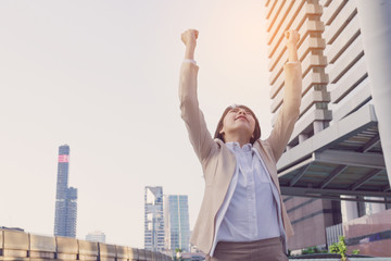 Winner woman celebrating success on city background.