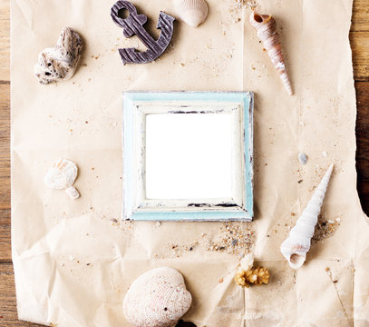 vintage wooden photo frame on craft paper with sand and sea shells mock up. Travel, summer concept. Text space
