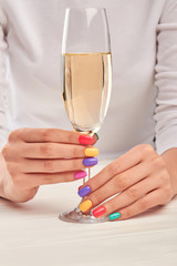 Glass of champagne in manicured hands. Gentle woman hands with stylish summer manicure holding glass with champagne. Female beauty and elegance.