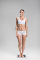 Fototapeta premium Cheerful fit girl weighing on balance