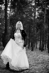 A runaway bride in a wedding dress and a leather jacket in the forest. Difficulties at the wedding. Fashionable girl in grunge style