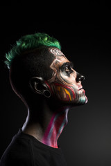 Side view of man with scary makeup isolated on black background. Face art, colored mystical makeup on mans face.