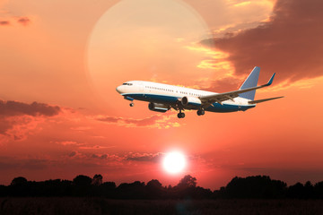 Odrzutowy samolot pasażerski na tle zachodzącego słońca.
