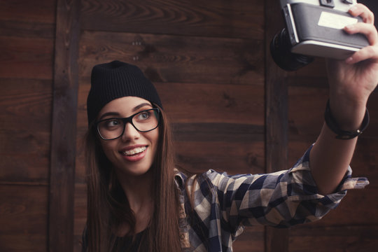 Hipster girl in glasses and black beanie with vintage camera