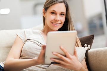 Portrait of a smiling young woman using a tablet computer in her apartment