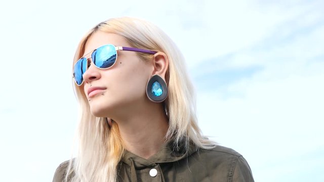 bodimodification, portrait of a girl with face piercings and tunnels in the ears. 4k, slow-motion shooting, copy space