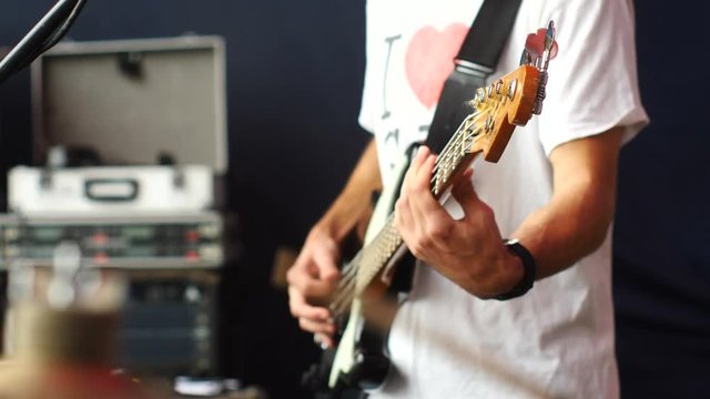 Drummer and Bassist plays bass guitar. On a stage.