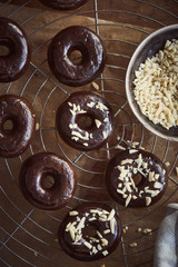 Schokoladen Donuts frisch gebacken auf Metallgitter, Streusel Mandelsplitter