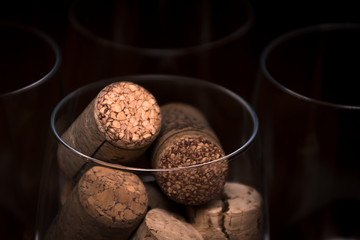 Catering, party concept: close-up image of wine glass with corks and empty glasses on a dark wooden background. Selective focus.