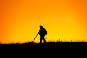 Silhouette of photographer walking top of mountain at sunset time.Sky background.