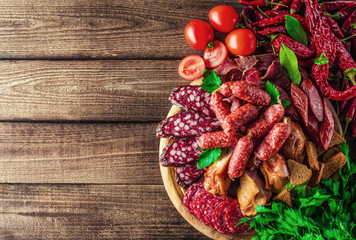 Food tray with delicious salami, pieces of sliced ham, sausage, tomatoes, salad and vegetable.