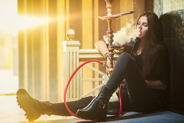 Concept: recreation, millennial, nightlife. Beautiful young woman smoke hookah on floor of empty...
