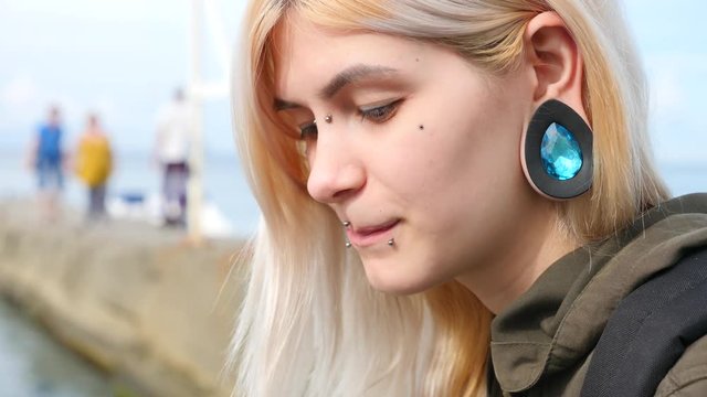 bodimodification, portrait of a girl with face piercings and tunnels in the ears. a girl with a split tongue. shows the language. 4k, slow-motion shooting, copying space