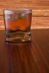 Glass of wiskey and ice on wooden background