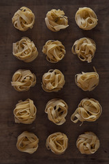 gerollte Tagliatelle angeordnet auf Holztisch von oben