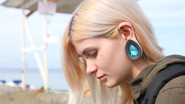 bodimodification, portrait of a girl with face piercings and tunnels in the ears. 4k, slow-motion shooting, copy space