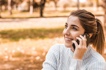 Young beautiful smiling woman talking on cell phone in park.