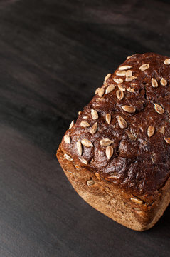 Delicious close up fresh baked brown bread with bran sunflower seeds on a dark background, vertical image