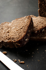 delicious fresh baked slices of bread with sunflower seeds on a dark table, vertical image